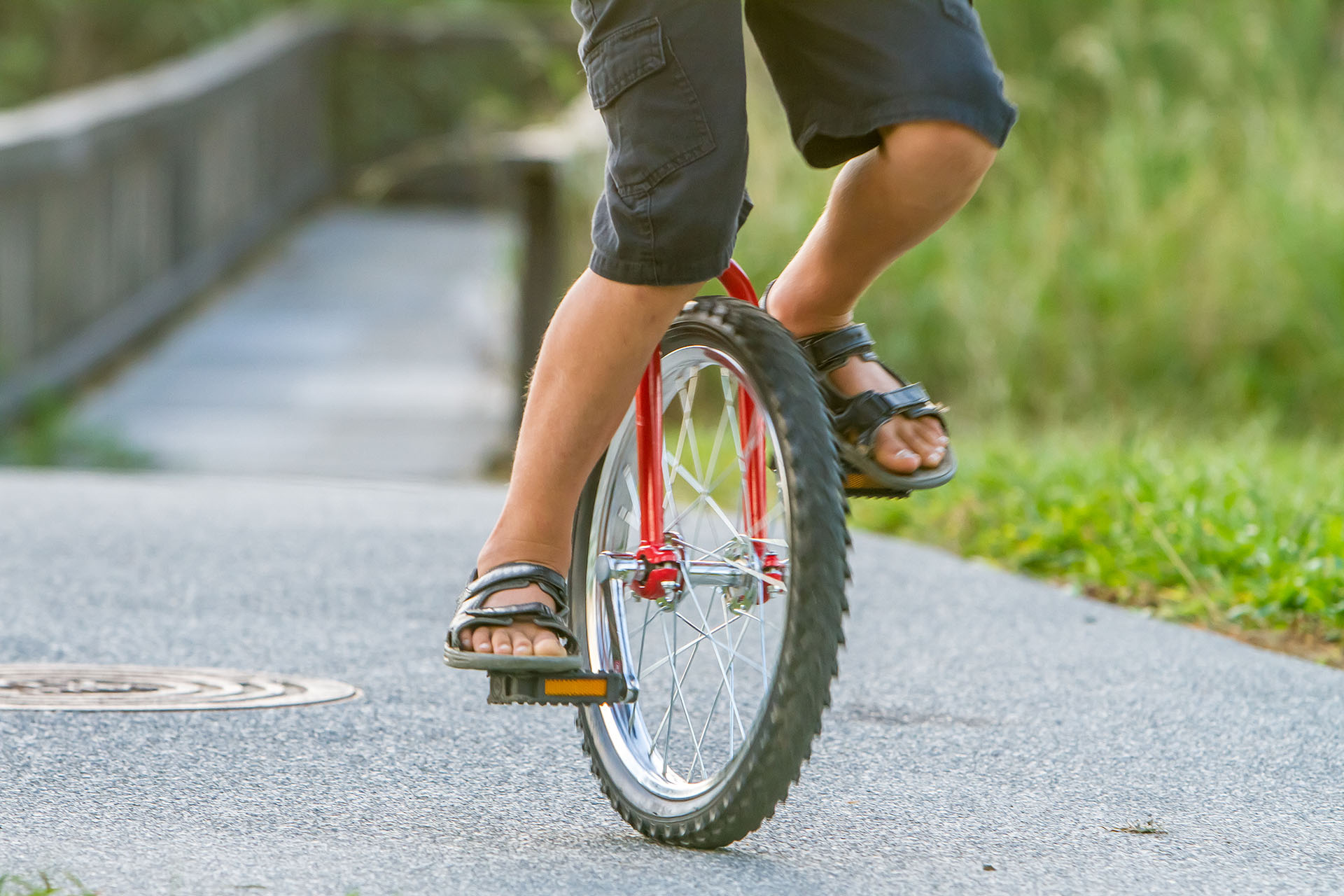 outdoor portrait of young boy riding a unicycle (one wheel bike) on natural background