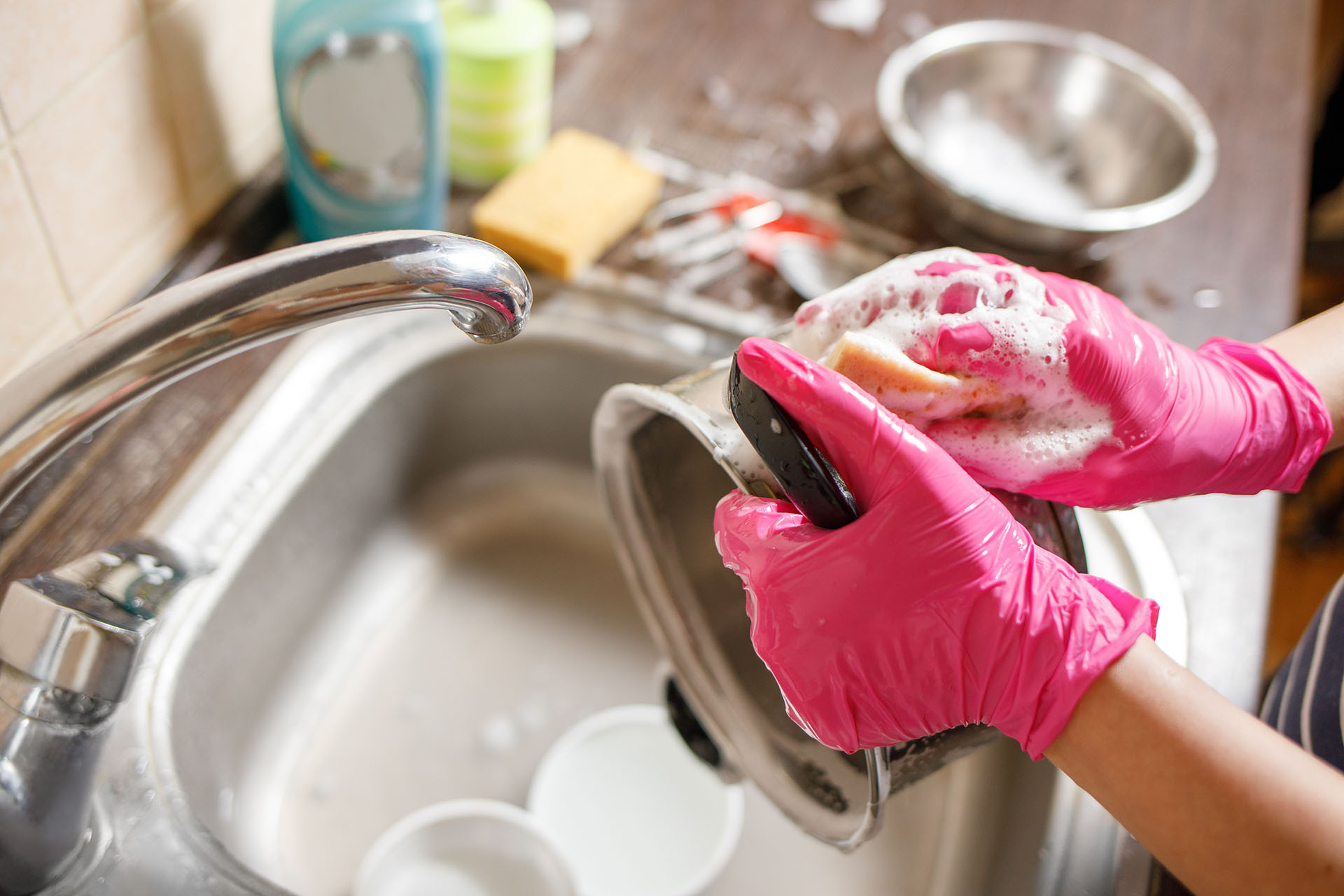 Woman in rubber gloves washing up dishes and pot. Stay home clean house