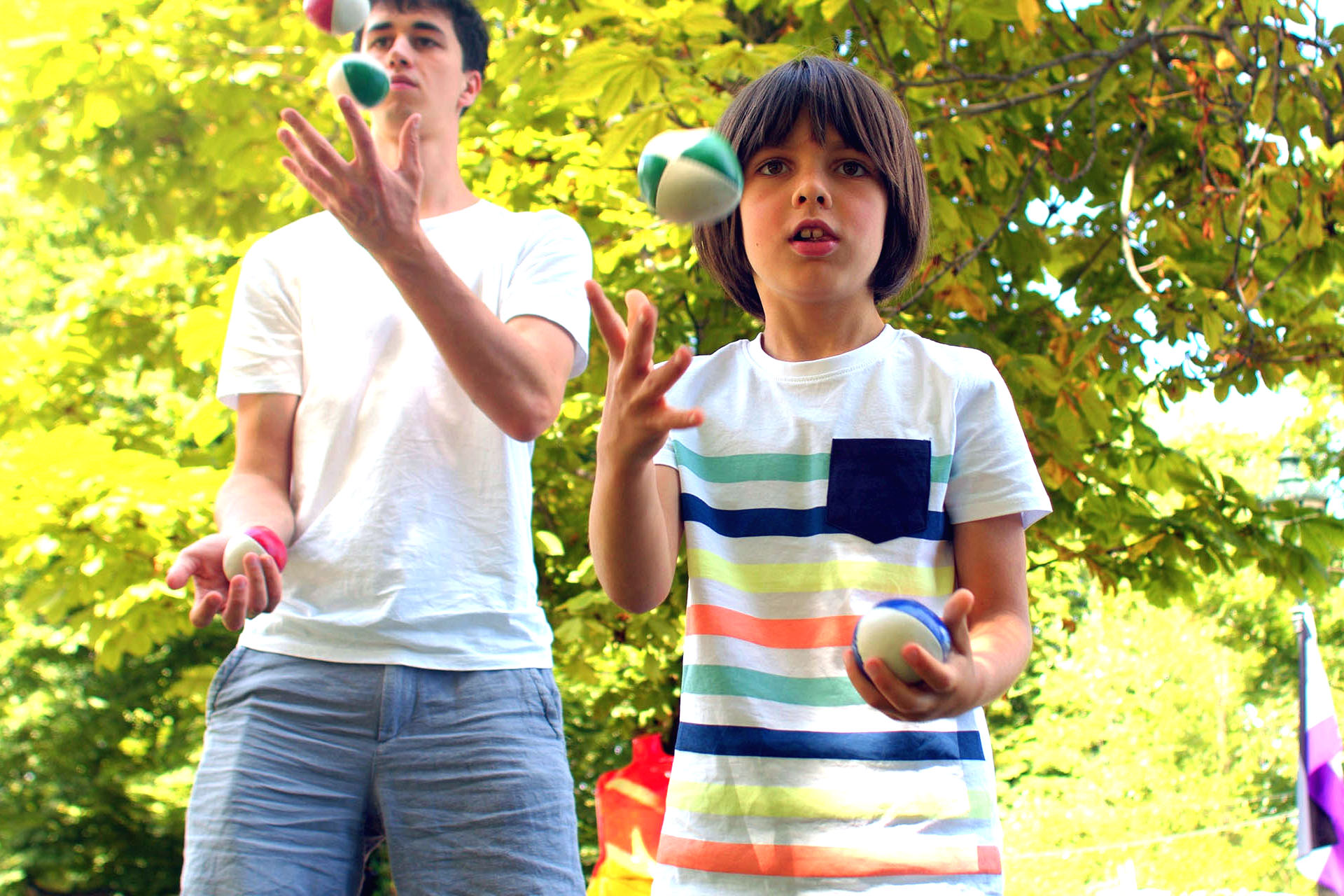 Boy and young teacher with balls. Learning to juggle accelerates the growth of neural connections related to memory, focus, movement, and vision.