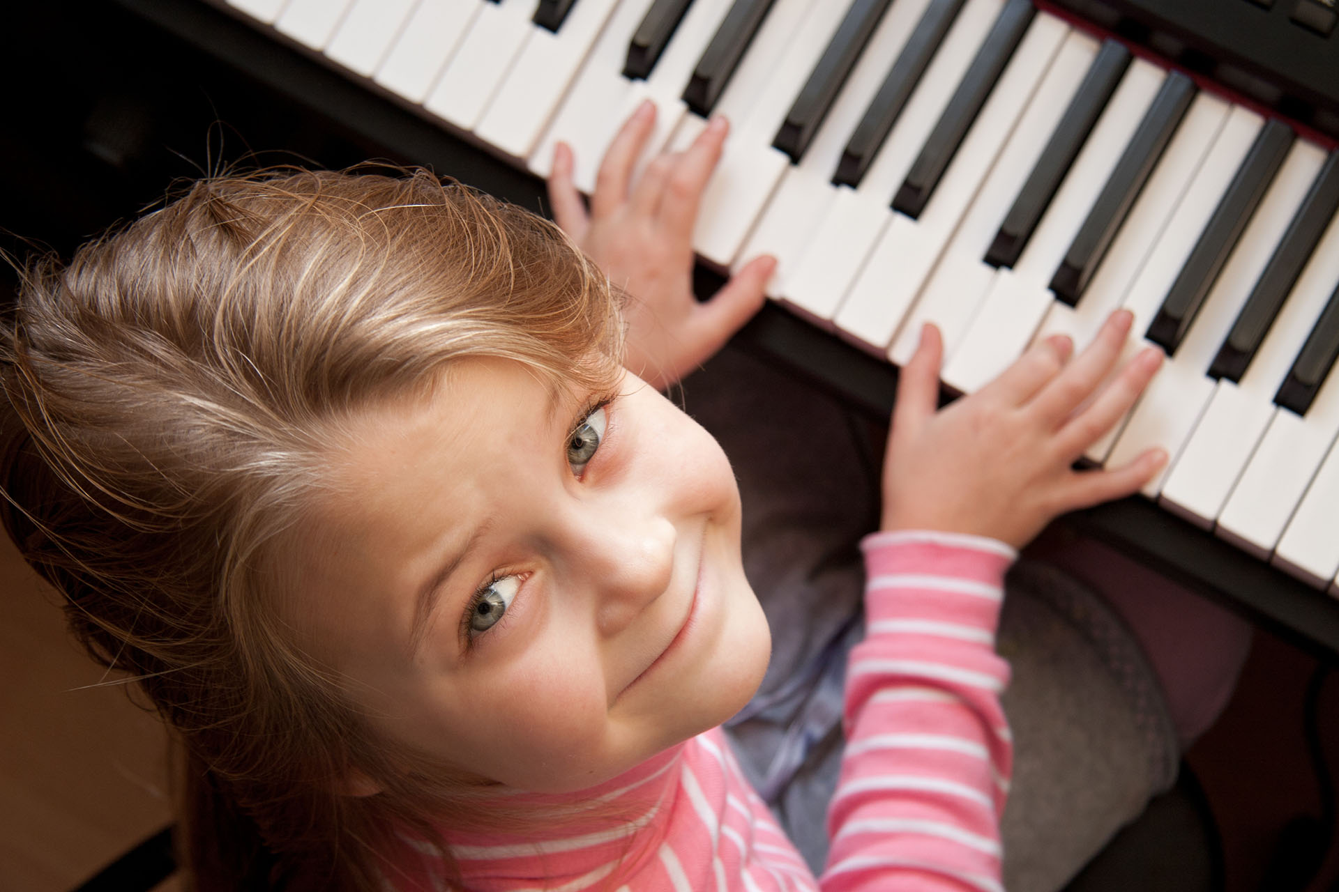 Young girl sitiing at digital  piano